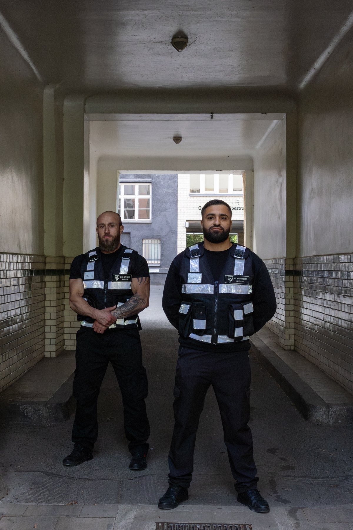 Zwei Mitarbeiter von BROCKEN Sicherheit in Dienstkleidung mit Warnweste stehen in einem gefliesten Hausdurchgang
